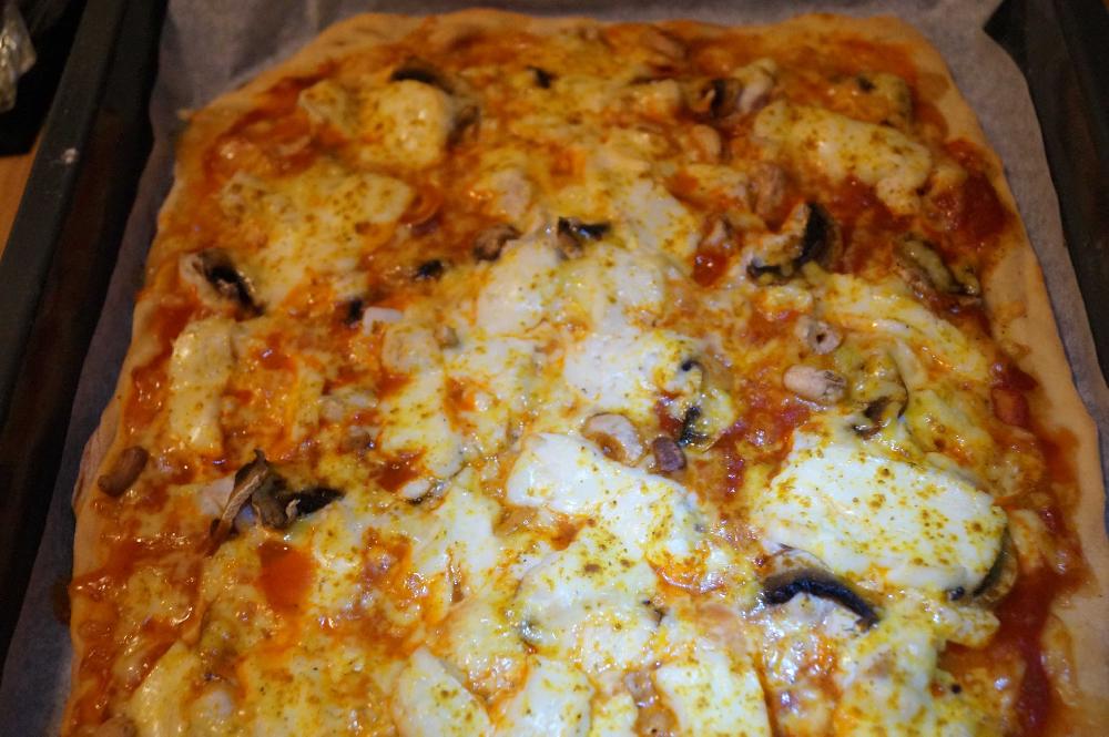 Pizza with chicken, curry, halloumi cheese, and cashew nuts picture